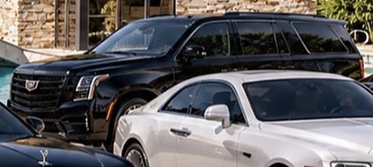 Black Cadillac Escalade SUV parked behind a white Rolls-Royce